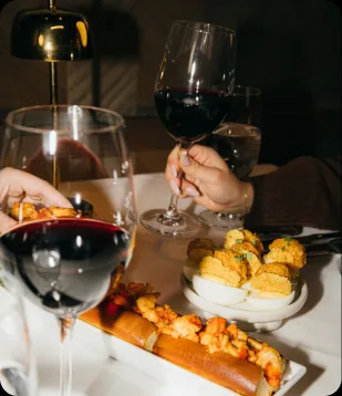 A glass of red wine beside a lobster and deviled-egg plate at Steak 48
