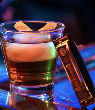 A whiskey cocktail beside a harmonica at House of Blues